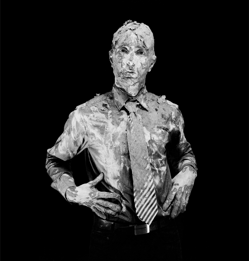 Black white photo of Matthias Mollner dressed in a shirt and a tie and besmeared with earth-moist clay