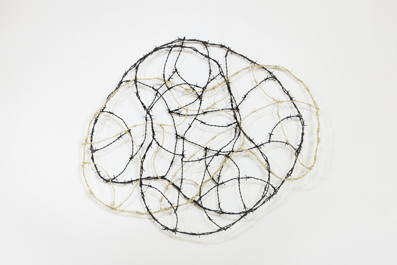 A wall object in the shape of a cloud made of painted barbed wire