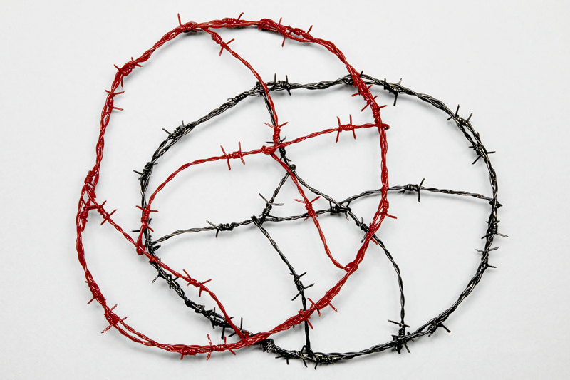 A wall object in the shape of a cloud made of painted barbed wire