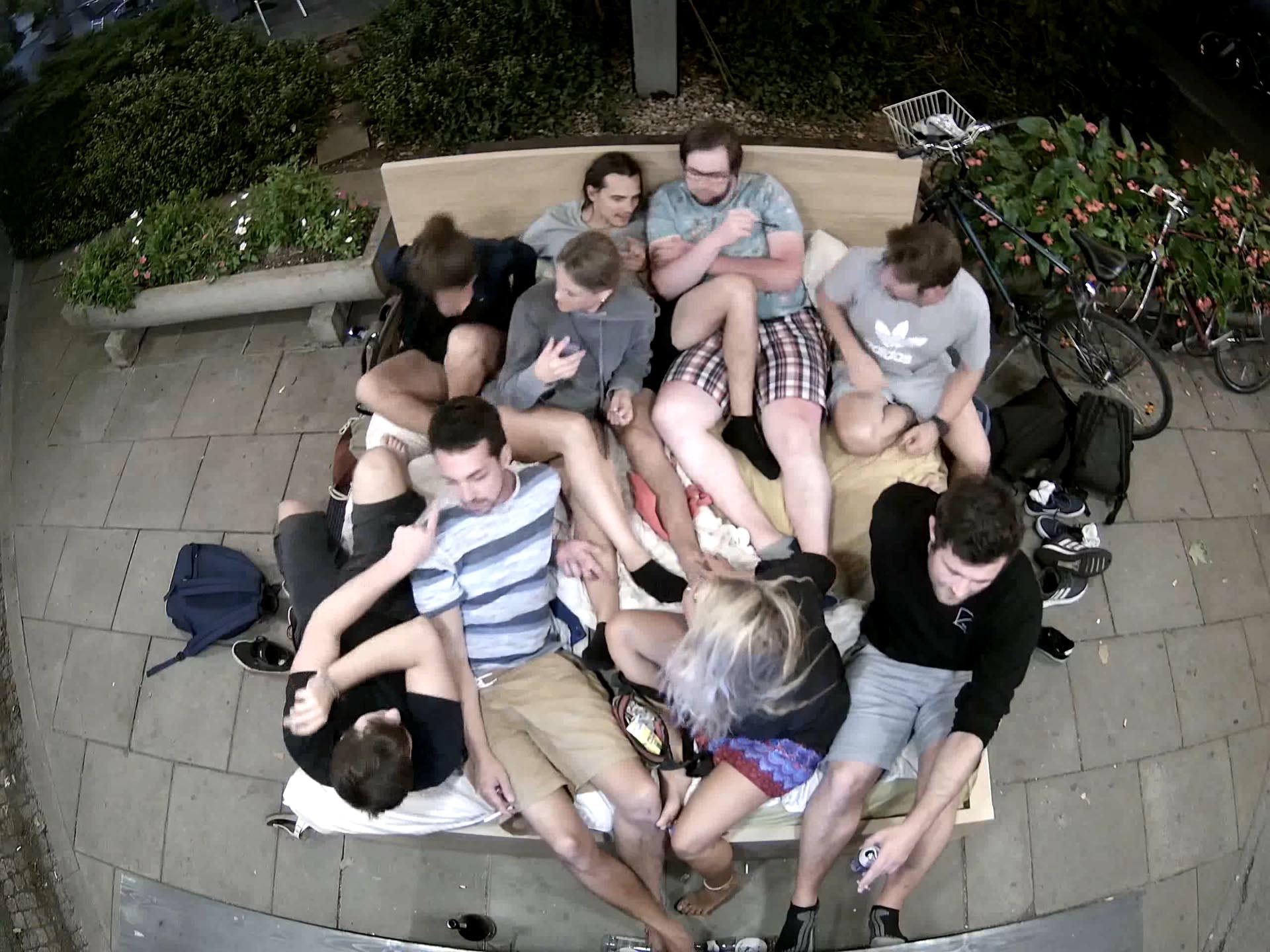 A group of people is lying and sitting in a big sized bed in public space in Graz