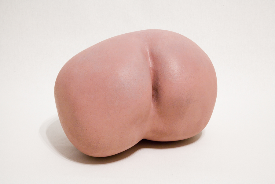 A pink painted concrete sculpture in the shape of a human's butt