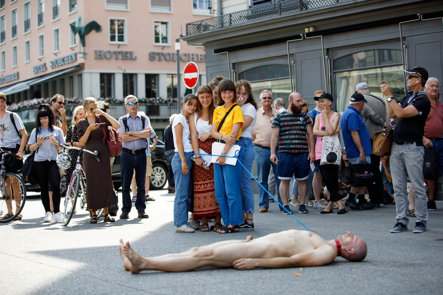 Matthias Mollner is lying naked on an asphalt floor in Zurich and is being pulled on a dog leash by several people